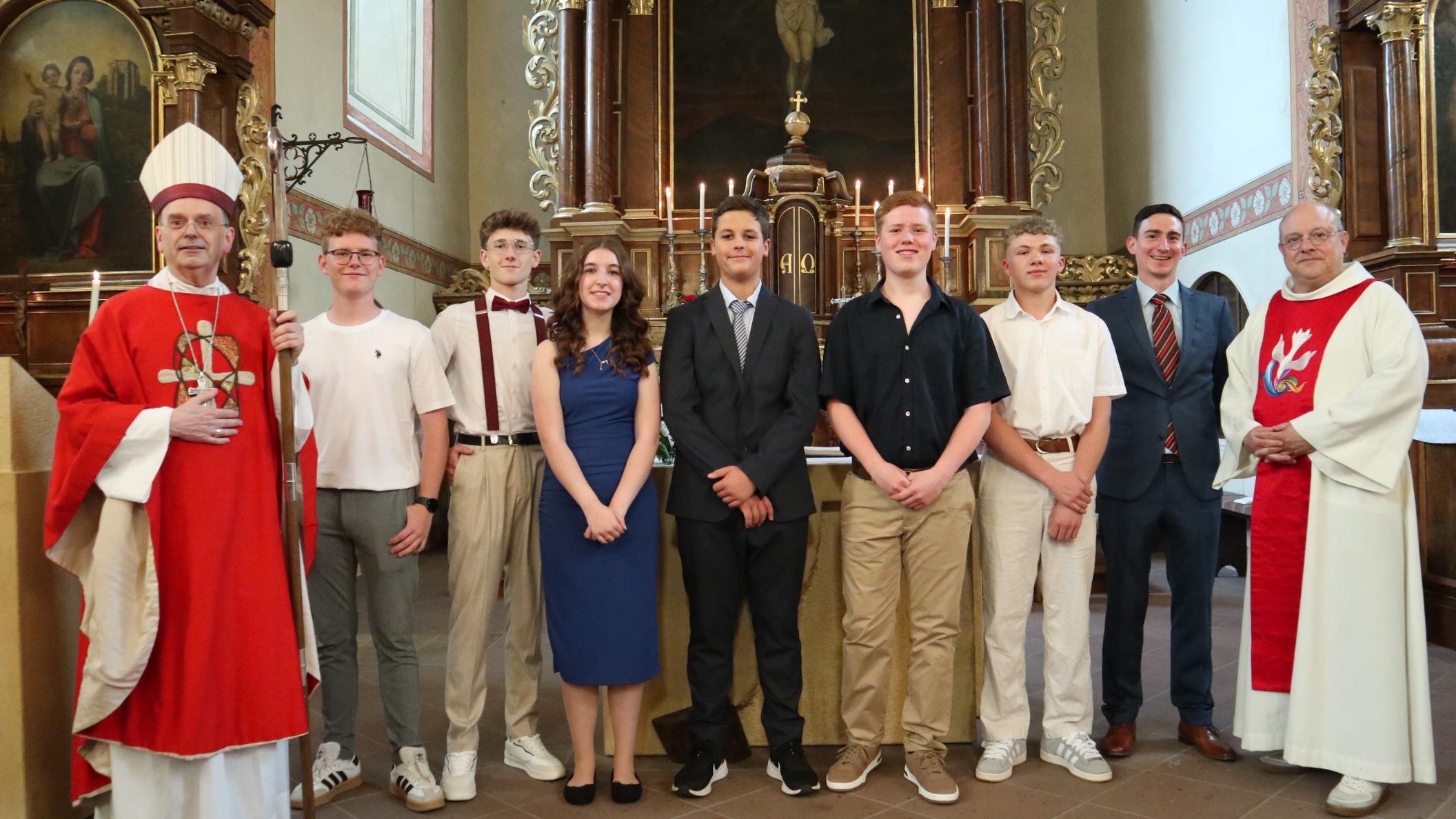 Weihbischof Robert Brahm (links), Pfarrer Michael Knipp (rechts) und Pastoralreferent Tobias Petry (Zweiter v. rechts) gratulieren den jungen Menschen in der Kirche St. Nikolaus in Bacharach zu ihrer Firmung.